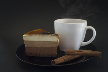 Cake on a black plate and coffee in a white Cup.