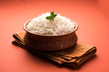 Cooked plain white basmati rice in terracotta bowl over plain or wooden background
