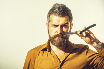 Portrait brutal caucasian hipster, unshaven man with vintage straight razor on neutral background....