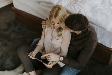 Happy couple sitting on the floor with tablet