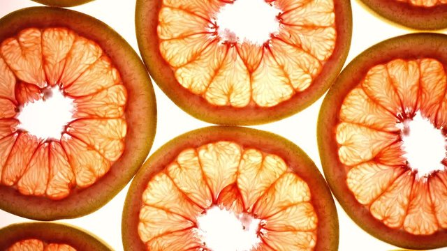 Amazing top view of grape-fruit slices in flat lay close up, rotating contra clockwise. Excellent food macro background with vibrant texture and backlight in UHD 4k, 3840x2160, clip.
