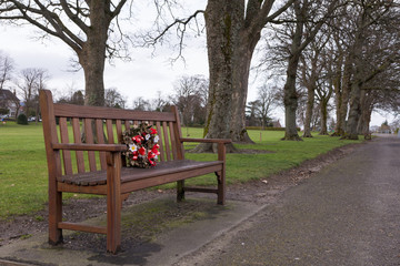a wreath placed on a park bench as a memorial 
