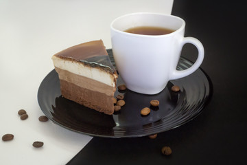 Cake on a black plate and coffee in a white Cup.