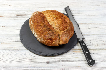 bread loaf with knife on Black Slate Board. Top view