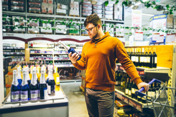 man choose alcohol in store. shopping concept. bottle in man hands