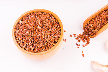 Grains of red rice in a glass bowl and garlic on a light table - healthy eating concept