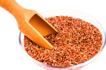 Grains of red rice in a bowl close-up on a white background, isolate - healthy eating concept, copy...