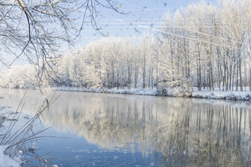 Paisaje nevado con reflejo de árboles nevados en el río