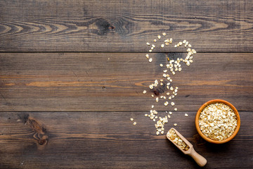 Cereals concept. Oatmeal in bowl on dark wooden background top view copy space