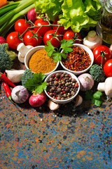 assortment of spices and fresh organic vegetables on a dark background, vertical