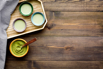 Japanise tea ceremony with matcha tea. Bowl with powder and cups with beverage on tablecloth on dark wooden background top view copy space