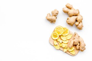 Fresh ginger root and lemon slices pattern on cutting board on white background top view copy space