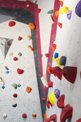 Grey wall with climbing holds and ropes in gym.