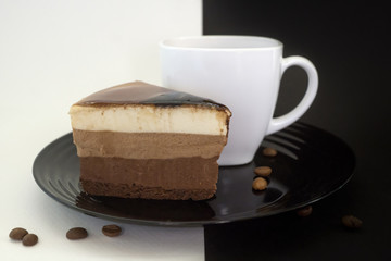 Cake on a black plate and coffee in a white Cup.