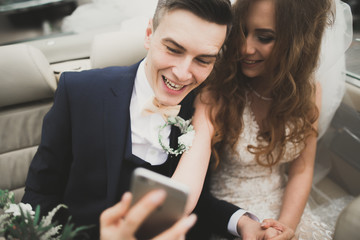 Happy groom is taking selfie with his pretty bride on wedding day
