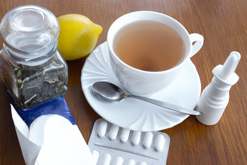 A cup of tea with medicines and a handkerchiefs