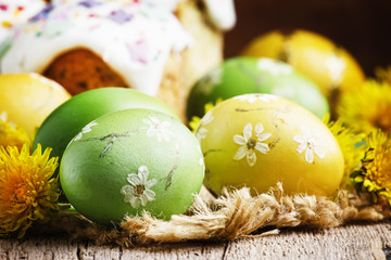 Easter green and yellow painted eggs, white apricot flowers, spring festive composition in rustic...