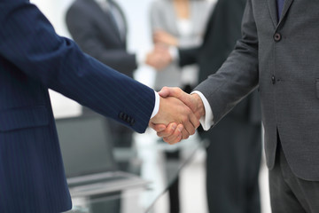 Business partners handshaking over business objects on workplace