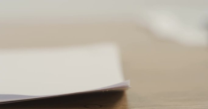 Close up of the papers lying on the desk and woman's hand doing holes by stepler. Macro