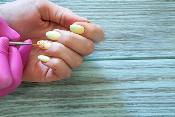 Мастер по маникюру рисует цыпленка и пасхальные яйца на ногтях.