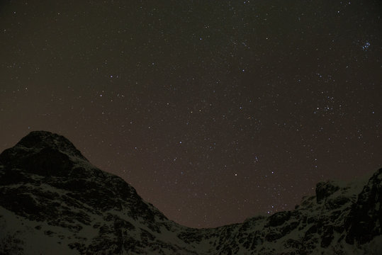 Clear sky during a starry night above the mountains surrounding a Norwegian fjord