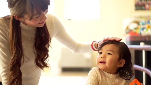 母と一緒に玩具で遊ぶ女の子（1才児）