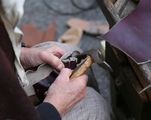 cobbler repairs the shoe with an ancient hammer and the piece of leather