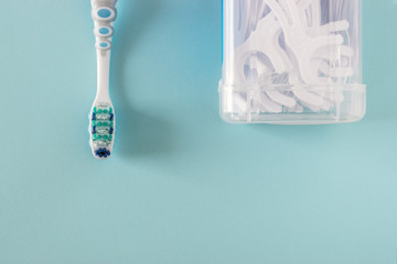 Toothbrush and dental floss on bright blue background.