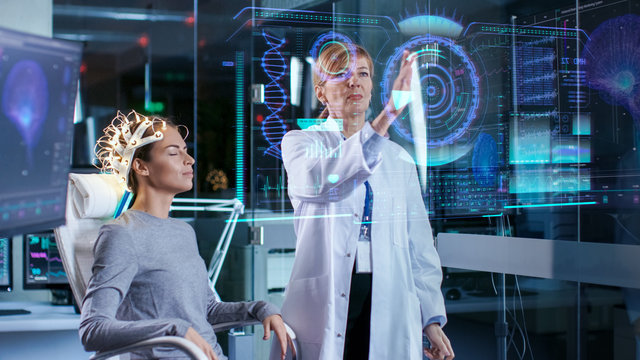 Woman Wearing Brainwave Scanning Headset Sits in a Chair while Scientist  Using Futuristic Holografic Interface. In the Modern Brain Study Laboratory  Monitors Show EEG Reading and Brain Model. Stock Photo | Adobe Stock