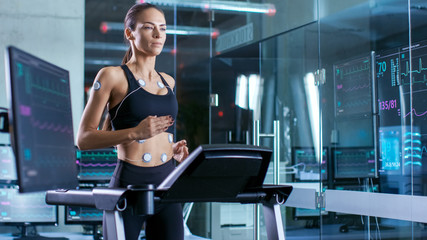 Beautiful Woman Athlete Runs on a Treadmill with Electrodes Attached to Her Body, Female Physician Uses Tablet Computer and Controls EKG Data Showing on Laboratory Monitors.