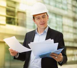 Smiling male architect in helmet with documents