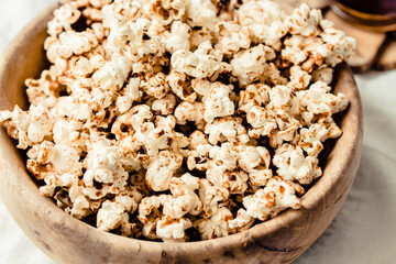 Sweet caramel vegan popcorn in a wooden plate. Snack for the movie. Rustic.light background. Macro, close-up.