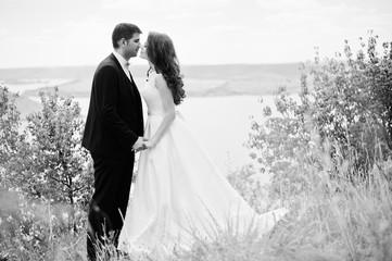 Wedding couple at breathtaking landscape with rock and lake.