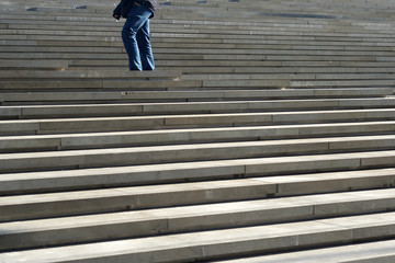 A man in a jeans pants climbing up the outdoor staircase