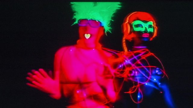glow raver man and woman tied up together with led cables, filmed in fluorescent clothing under UV black light. this version has overlayed video distortion and glitch effects