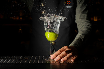 Bartender hand holding a glass of splashing Caipirinha cocktail