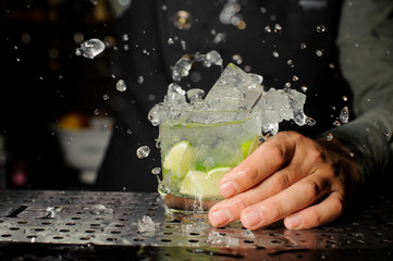 Bartender hand holding a glass filled with Caipirinha cocktail
