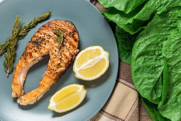 Salmon fillet. Grilled salmon with herb and lemon on plate. Fish roasted on a wooden background.
