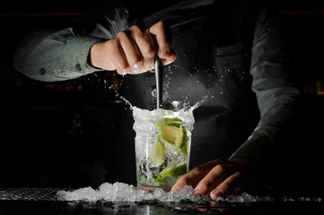 Poster Barman die met de hand vers sap uit limoen perst en de Caipirinha-cocktail maakt © fesenko