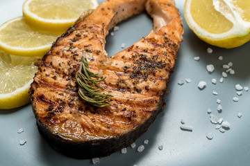 Salmon fillet. Grilled salmon with herb and lemon on plate. Fish roasted on a wooden background.
