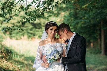 Groom kisses bride's shoulder tender standing in the forest