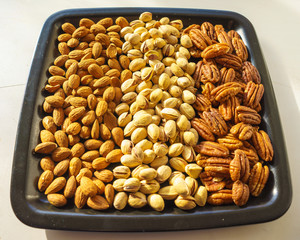 Nuts almonds, pistachios and pecans on black plate, close-up, set.  