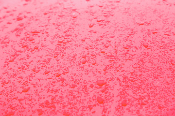 Droplets on red car surface, close up
