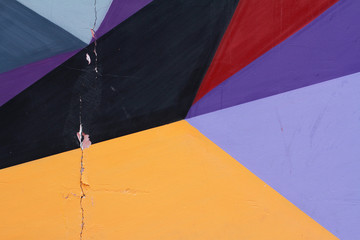Colorful (grey, purple, yellow, red and black) painted wall with cracks as background or texture