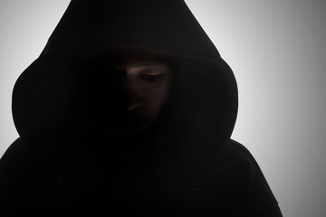 Man in hood / Hooded man in shadow on gray background.