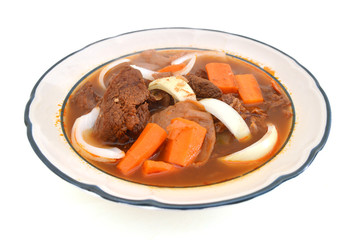 beef stew and vegetables in white platel on white background