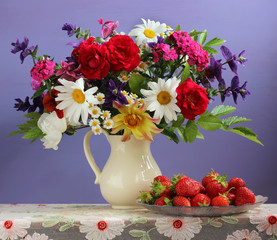 Bouquet of garden flowers in a jug and strawberries.