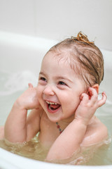 A little girl makes funny faces in the bath