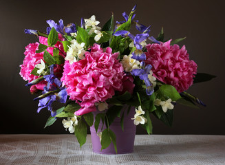 Peonies, irises and Jasmine in a bouquet. Garden flowers in a vase.