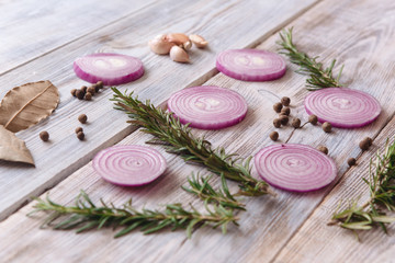 sliced onions and rosemary on white wooden background